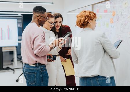 Brainstorming de jeune équipe pour l'expansion de l'entreprise dans un bureau d'entreprise. Collaboratifs et ciblés, ils discutent des statistiques et élaborent des stratégies pour réussir. Banque D'Images