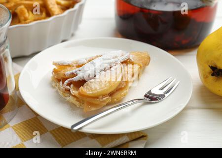 Morceau de savoureuse tarte au coing maison avec du sucre en poudre servi sur une table en bois blanc Banque D'Images