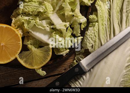 Chou chinois frais, citron et couteau sur table en bois, plat Banque D'Images