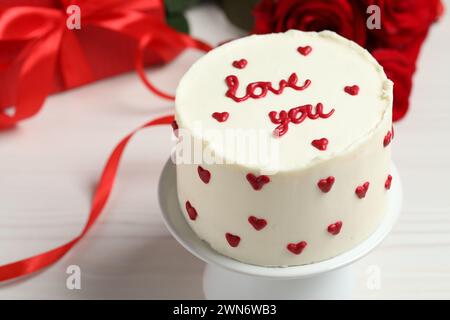 Bento gâteau avec texte Love You, boîte cadeau et roses sur table en bois blanc, gros plan. Prog Surprise pour la Saint-Valentin Banque D'Images