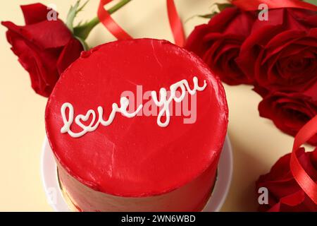 Bento gâteau avec texte Love You et roses rouges sur la table beige, gros plan. Prog Surprise pour la Saint-Valentin Banque D'Images