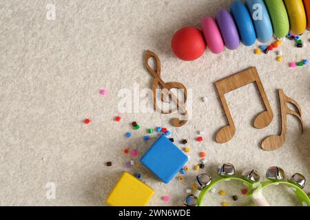 Concept de chanson de bébé. Notes en bois, instruments de musique pour enfants et jouets sur tapis beige, pose à plat. Espace pour le texte Banque D'Images