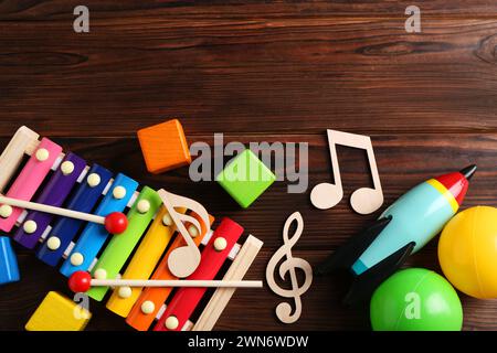 Concept de chanson de bébé. Notes en bois, xylophone et jouets sur table, pose à plat. Espace pour le texte Banque D'Images