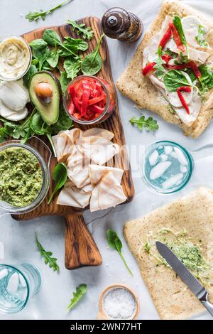 Ingrédients sur une planche de bois pour faire des wraps de dinde au pesto frais. Banque D'Images