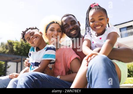 Père afro-américain et mère biraciale sourient avec leur fils et leur fille à l'extérieur Banque D'Images