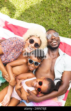 La famille afro-américaine profite d'une journée ensoleillée à l'extérieur, allongée sur une couverture rayée Banque D'Images