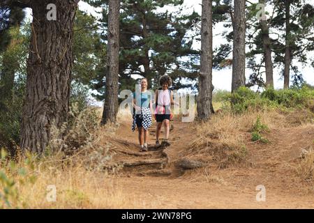 Deux femmes font de la randonnée sur un sentier forestier, entouré de grands arbres, avec un espace de copie Banque D'Images