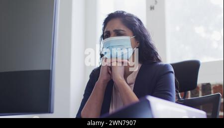 Image du traitement des données financières sur femme d'affaires portant un masque facial Banque D'Images