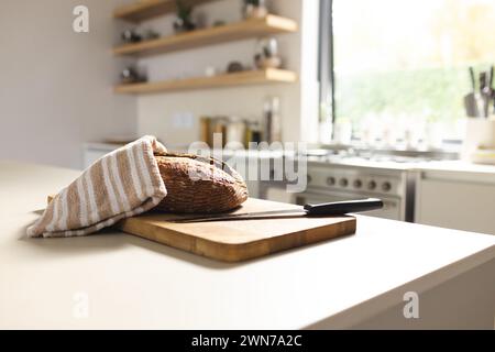 Le pain fraîchement cuit repose sur une planche à découper en bois dans une cuisine lumineuse, avec espace copie Banque D'Images