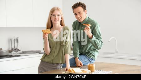 Heureux jeune couple avec de savoureux toasts au beurre de noix dans la cuisine Banque D'Images