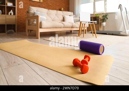 Tapis de fitness avec haltères et rouleau en mousse à l'intérieur du salon Banque D'Images