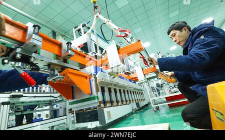 ZHANGYE, CHINE - 29 FÉVRIER 2024 - des travailleurs soulèvent des modules sur une ligne de production automatisée pour la fabrication de modules d'équipement de stockage d'énergie Banque D'Images