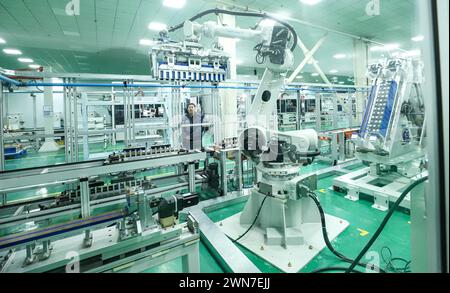 ZHANGYE, CHINE - 29 FÉVRIER 2024 - Un membre du personnel observe le fonctionnement d'un robot de module de stockage d'énergie sur une ligne de production automatisée pour e. Banque D'Images