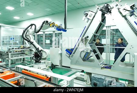 ZHANGYE, CHINE - 29 FÉVRIER 2024 - Un membre du personnel observe le fonctionnement d'un robot de module de stockage d'énergie sur une ligne de production automatisée pour e. Banque D'Images