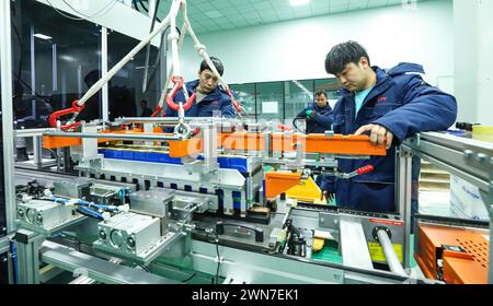 ZHANGYE, CHINE - 29 FÉVRIER 2024 - des travailleurs soulèvent des modules sur une ligne de production automatisée pour la fabrication de modules d'équipement de stockage d'énergie Banque D'Images