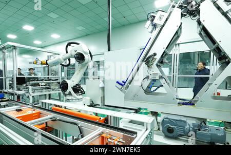 ZHANGYE, CHINE - 29 FÉVRIER 2024 - Un membre du personnel observe le fonctionnement d'un robot de module de stockage d'énergie sur une ligne de production automatisée pour e. Banque D'Images