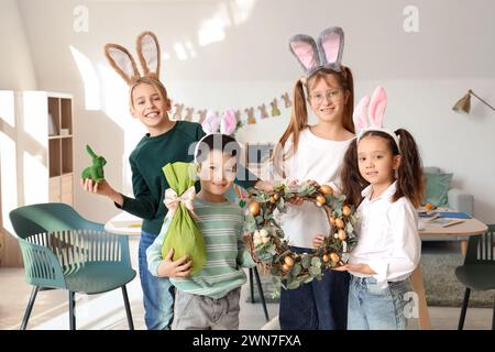 Petits enfants en oreilles de lapin avec couronne de Pâques et œuf cadeau à la maison Banque D'Images