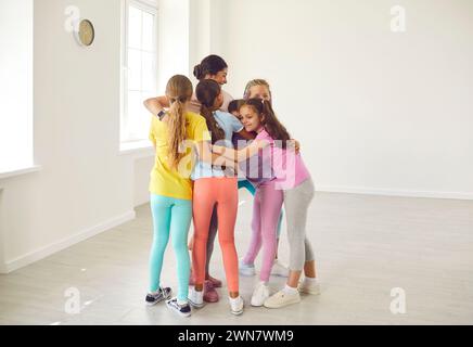 Groupe d'enfants heureux embrassant leur entraîneur sportif ou professeur de danse après le cours Banque D'Images