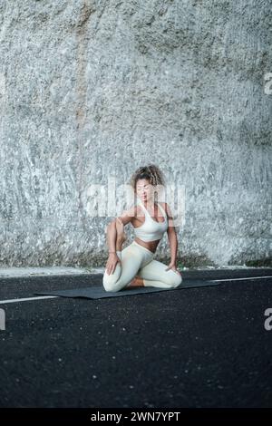 Une jeune femme latina fait un asana de yoga sur fond de rocher blanc. Banque D'Images