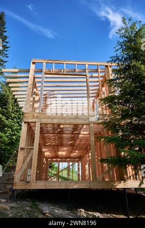 Bâtiment résidentiel avec ossature en bois en cours de construction près d'une forêt. Début de la nouvelle construction de chalet confortable. Idée de construction écologique, conception architecturale contemporaine Banque D'Images