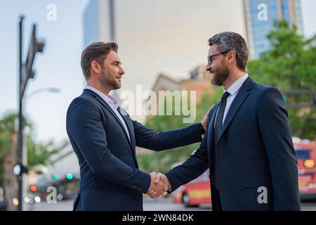 Travail d'équipe réussi. Des gens d'affaires se serrant la main. Poignée de main entre deux hommes d'affaires. Deux hommes d'affaires serrant la main sur la rue de la ville. Hommes d'affaires dans Banque D'Images