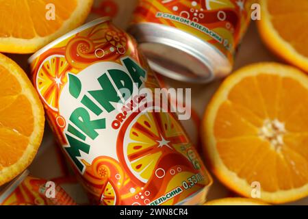 KIEV, UKRAINE - 7 JUILLET 2023 Mirinda boisson orange avec de nombreuses oranges fraîches sur fond coloré Banque D'Images