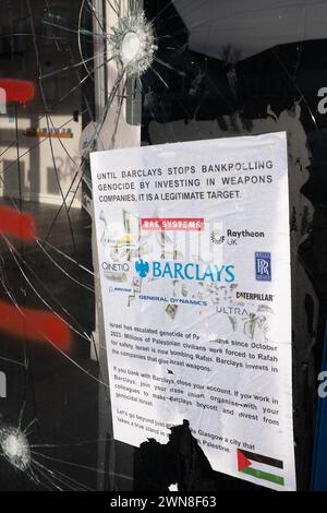Glasgow, Royaume-Uni, 1er mars 2024. Fenêtres brisées et graffitis lisant « Barcleys Funds génocide » et « Free Palestine » sur la Barclays Bank dans le quartier Shawlands de Glasgow, en Écosse, le 1er mars 2024. Photo de Jeremy Sutton-Hibbert/Alamy Live News. Banque D'Images