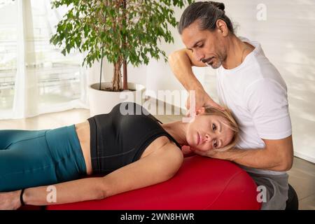 Physiothérapeute concentré manipulant la colonne vertébrale du patient pour soulager les douleurs cervicales en médecine alternative lors de la consultation en clinique moderne Banque D'Images