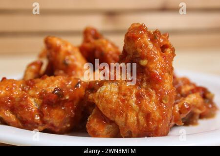 Un gros plan d’ailes de poulet étouffées de sauce, servies sur une assiette blanche Banque D'Images