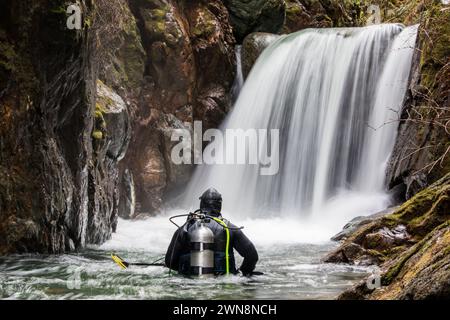 Vue arrière d'un plongeur debout dans la rivière regardant la cascade Banque D'Images