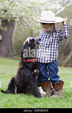 Garçon avec chapeau de papa, bottes et chien Banque D'Images