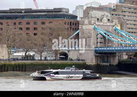 Un bateau fluvial Uber passe devant Tower Bridge et la Tour de Londres un matin de février. Banque D'Images