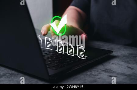 La femme utilise un ordinateur portable avec une interface VR pour le processus de gestion de la qualité et de validation. Assurance qualité et concept de certification. Banque D'Images