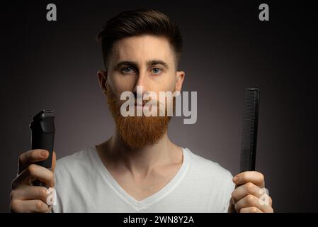 Homme rasant les moustaches cheveux par lui-même, auto-coupe de cheveux à la maison devant le miroir dans le bain. Homme avec coupe longue à l'aide de la tondeuse pour machine à raser. Banque D'Images