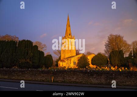 Lever de soleil à l'église St Peter dans le village de Sharnbrook, Bedfordshire, Angleterre, Royaume-Uni. Le cimetière et son mur de pierre environnant sont également visibles Banque D'Images