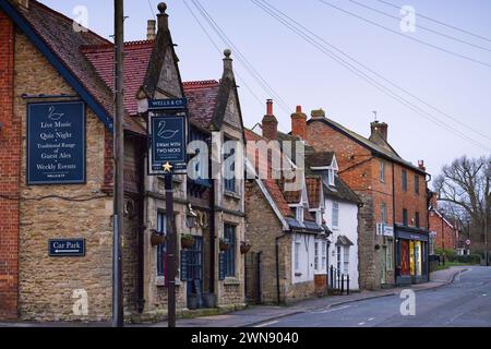 Sharnbrook, Bedfordshire, Angleterre, Royaume-Uni - magasin coopératif, clinique vétérinaire, pub Swan et chalets dans la rue principale du village par un matin ensoleillé Banque D'Images