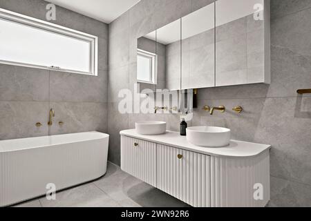 Une salle de bains moderne avec deux lavabos, miroir et baignoire spacieuse Banque D'Images