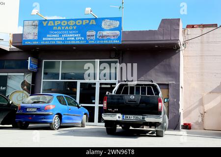 Véhicules garés devant Paulos Water Supplies sur la route vers Athènes Grèce Banque D'Images