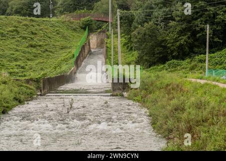 L'eau coule rapidement vers le bas du déversoir dans une petite rivière après des pluies torrentielles de mousson en Corée du Sud Banque D'Images