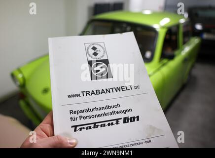 PRODUCTION - 09 février 2024, Saxe, Zwickau : Frank Hofmann détient le manuel de réparation original pour le Trabant 601, qu'il a réédité, dans le garage de sa société Trabandout. Le détaillant en ligne propose toutes les pièces du Trabant comme pièces de rechange. Il y a 60 ans, le Trabant 601 était présenté au public international lors de la Foire du printemps de Leipzig. Il a remplacé les modèles précédents Trabant 500 (P 50) et 600 (P 60). Jusqu'à la réunification, plus de 2,8 millions des 601 ont été construites à Zwickau, ce qui en fait le modèle Trabant le plus vendu. Les chiffres d'enregistrement en Allemagne ont de nouveau augmenté pour sev Banque D'Images