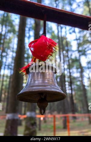 Cloches de bronze avec des tissus rouges : symbolisme spirituel au temple Tarkeshwar Mahadev, Uttarakhand, Inde Banque D'Images