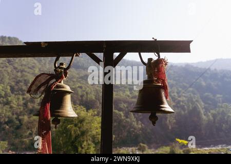 Cloches de bronze avec des tissus rouges : symbolisme spirituel au temple Tarkeshwar Mahadev, Uttarakhand, Inde Banque D'Images