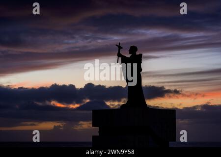 Statue de Sao Goncalo de Lagos (1360-1422) silhouette contre ciel nocturne à Lagos, Algarve, Portugal. Monument au saint patron de la ville tenant un Banque D'Images