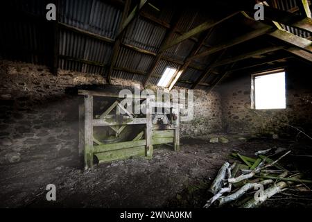 Une vieille machine de battage est abandonnée et oubliée dans une ancienne grange haute sur les collines des Highlands écossais Banque D'Images