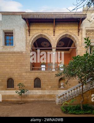 La cour sereine met en valeur la beauté intemporelle de l'architecture mamelouk avec de grandes arches et des pierres avec escalier accueillant menant à un balcon orné Banque D'Images