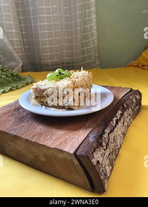 Délicieuse tarte froide au poulet garnie de purée de pommes de terre et de raisins sur une planche à découper en bois rustique avec espace de copie Banque D'Images