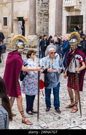 Acteurs en uniforme de soldats romains posant avec des touristes pour des photographies, palais de Dioclétien, Split, Croatie Banque D'Images