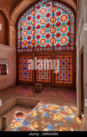 Un grand vitrail orné projette des éclaboussures de lumière colorées sur le sol du pavillon. Jardin de Dowlatabad, Yazd, Iran. Banque D'Images