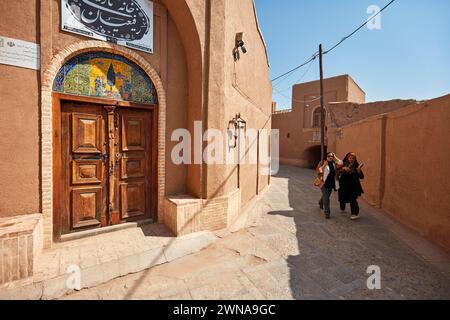 Deux iraniennes marchent dans une rue étroite près de la vieille maison de Rafiean dans le quartier historique de Fahadan à Yazd, en Iran. Banque D'Images