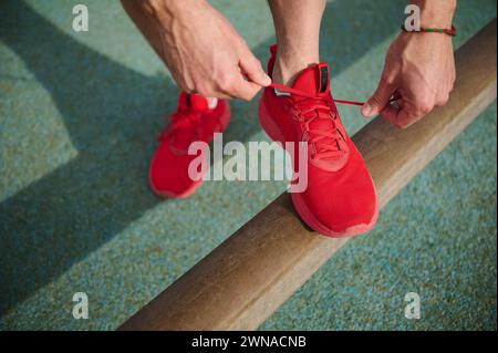 Vue d'en haut d'un sportif attachant des lacets de chaussures, se préparant pour courir le matin sur l'environnement urbain. Jeune homme actif courant jogging exercice dans th Banque D'Images